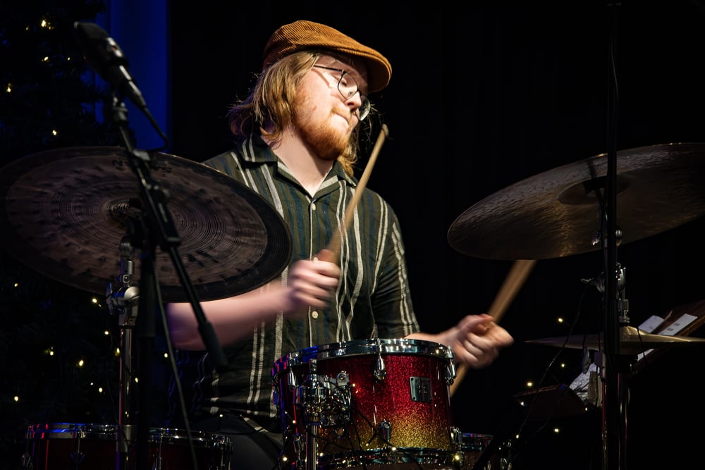 Person spelar trummor på en scen under en konsert.