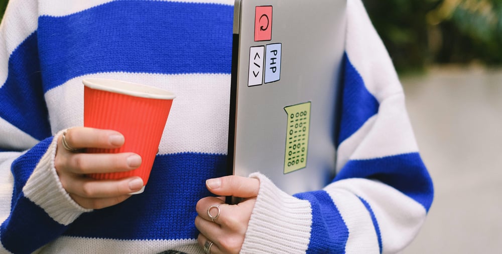 barn med randig tröja och en bärbar dator under armen.