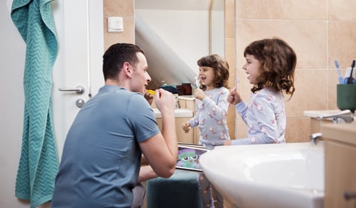 En man och ett barn borstar tänderna i ett badrum.