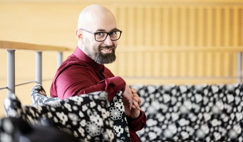 En man med glasögon sitter i en soffa.