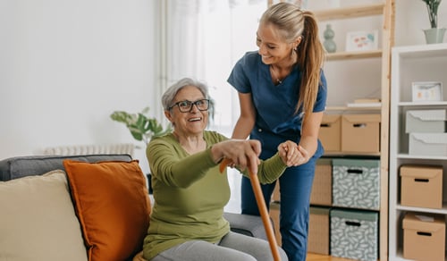 Sjukvårdspersonal hjälper äldre kvinna i sitt hem