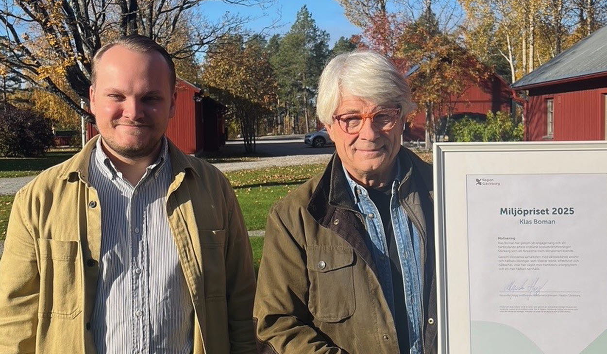 Två män står bredvid varandra i utomhusmiljö på hösten. Den ena håller i ett inramat diplom för Miljöpriset 2025.