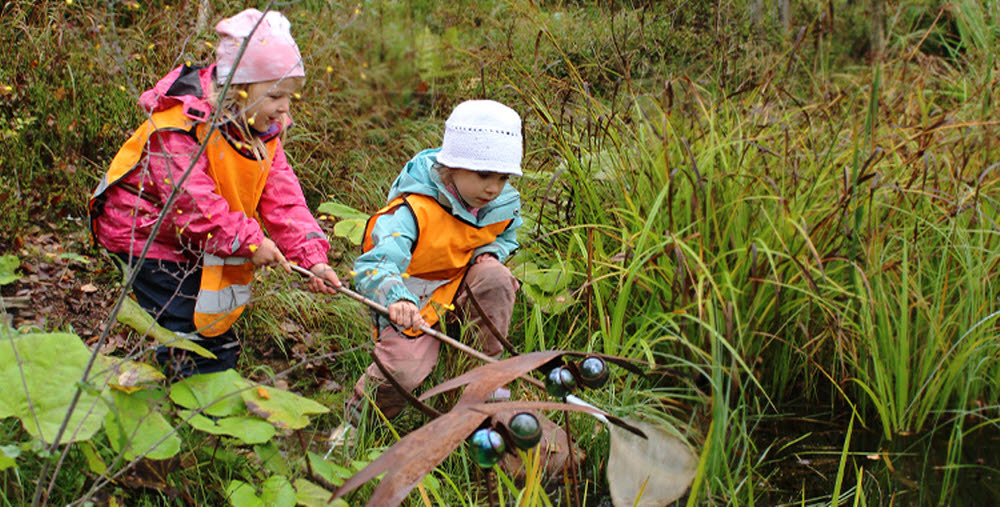Två barn leker i naturen