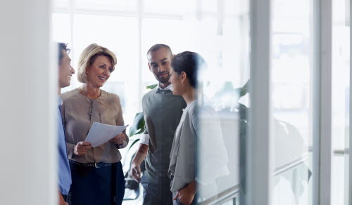 Smiling businesswoman discussing over document with colleagues in office