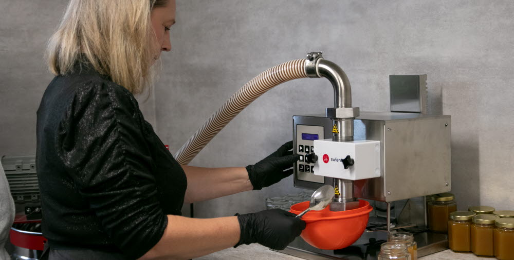 Kvinna tappar honung på burk.