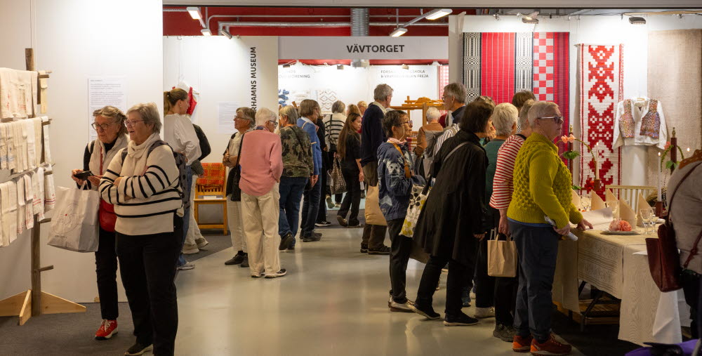 Många besökare samlade i området "VÄVTORGET", där vävda textilier och dukningar visas upp i olika montrar.